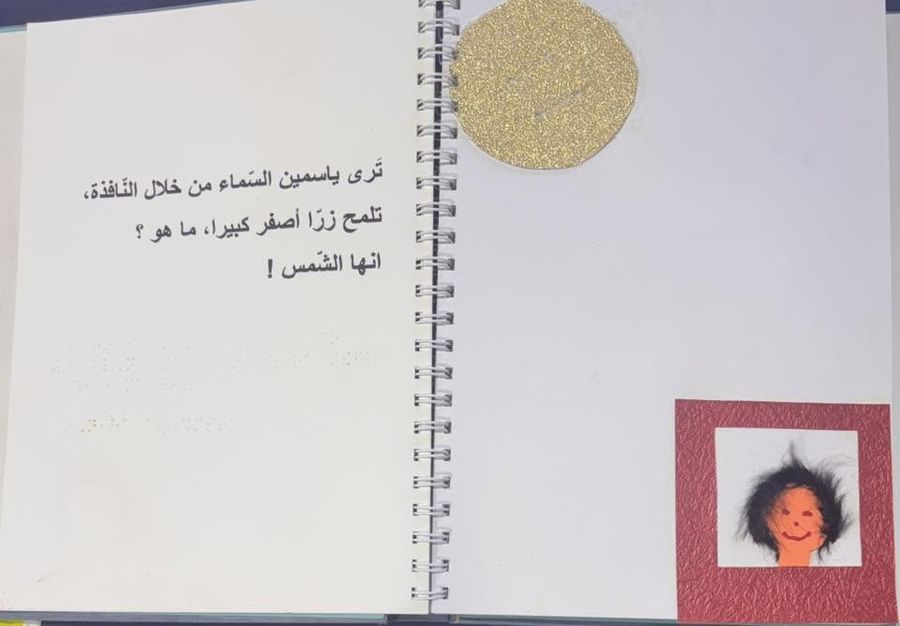 Page d'un livre tactile en braille et en arabe, avec un soleil en relief doré et un portrait en tissu texturé