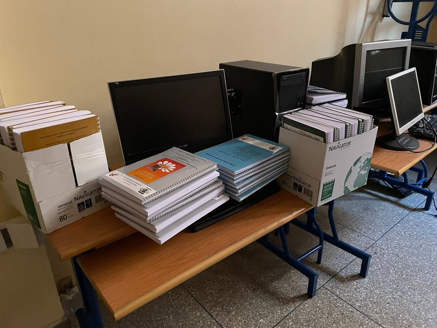 Cartons et piles de documents en braille prêts à être distribués, à côté de matériel informatique dans une salle de classe