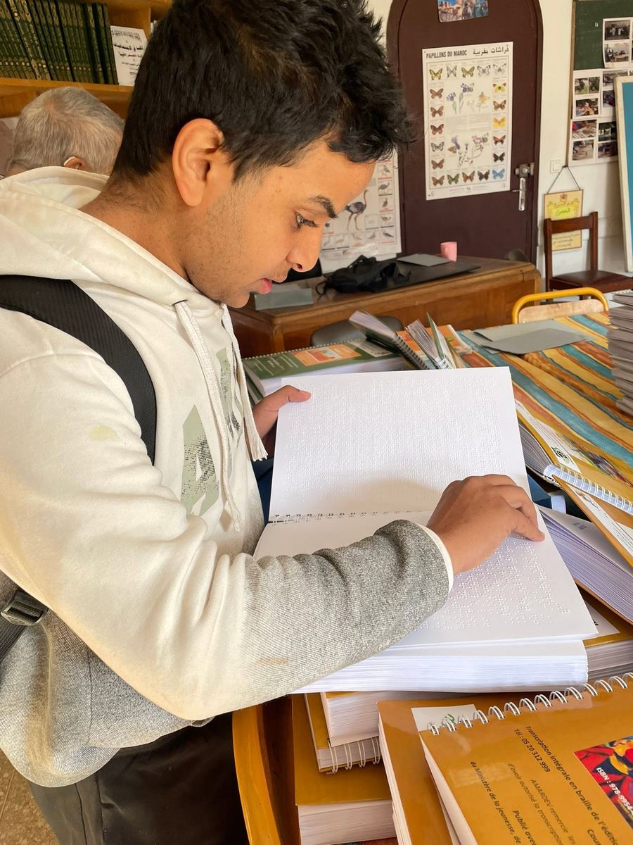 Un jeune élève lit attentivement une page en braille du bout des doigts