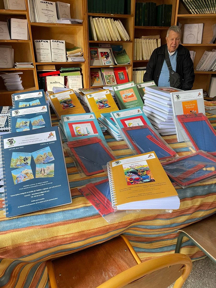 Des piles de livres en braille et des tablettes de lecture disposées sur une table, prêtes à être offertes aux élèves