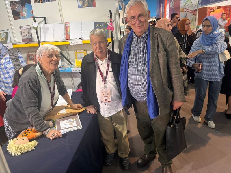 Trois bénévoles AMARDEV posent ensemble avec le sourire au stand du salon du livre
