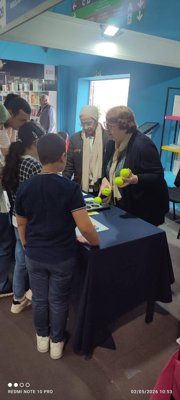 Une visiteuse fait découvrir un jeu tactile à un enfant sur le stand AMARDEV