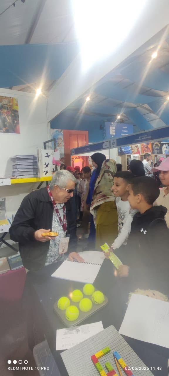 Un bénévole présente des jeux en relief à un groupe d'élèves sur le stand