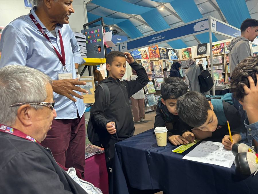 Des enfants s'initient à la lecture d'une planche en braille sur le stand AMARDEV