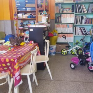 Salle de la ludothèque Touch'à Tout : étagères de livres et de jeux, table et chaises, tricycles adaptés pour les enfants